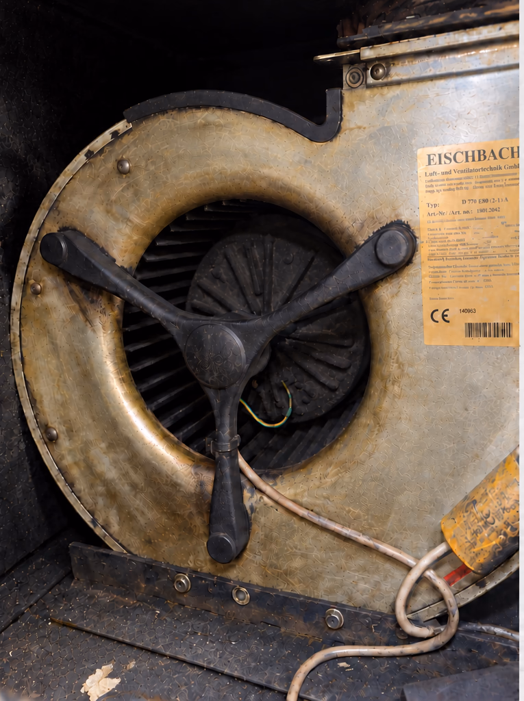 Ventilatiemotor met een dikke vetaanslag op het waaierhuis, voor reiniging.